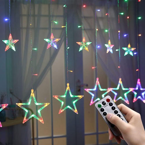Star-shaped LED string lights with a remote control in front of a window.
