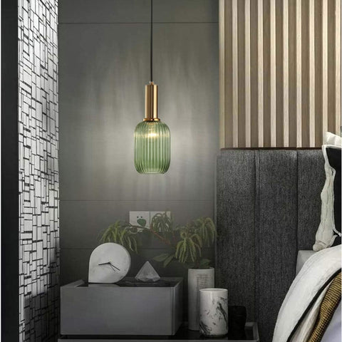 Green pendant light hanging above a nightstand with decorative items in a bedroom setting.
