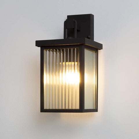 Black outdoor wall light fixture with glass panel on a white background