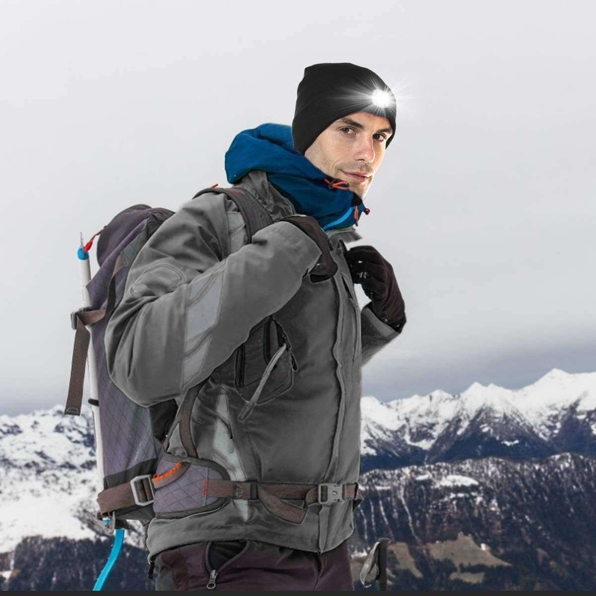 Person in winter clothing with a backpack against a snowy mountain background