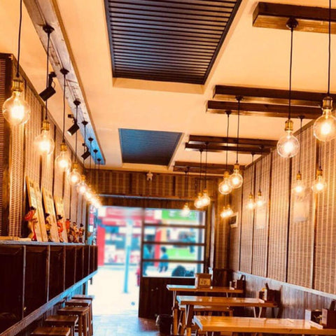 Interior of a restaurant with hanging lights and wooden tables.