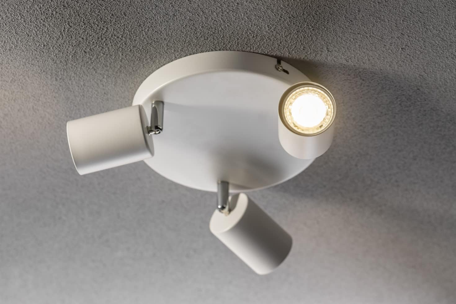 White ceiling light fixture with two adjustable arms on a gray ceiling.