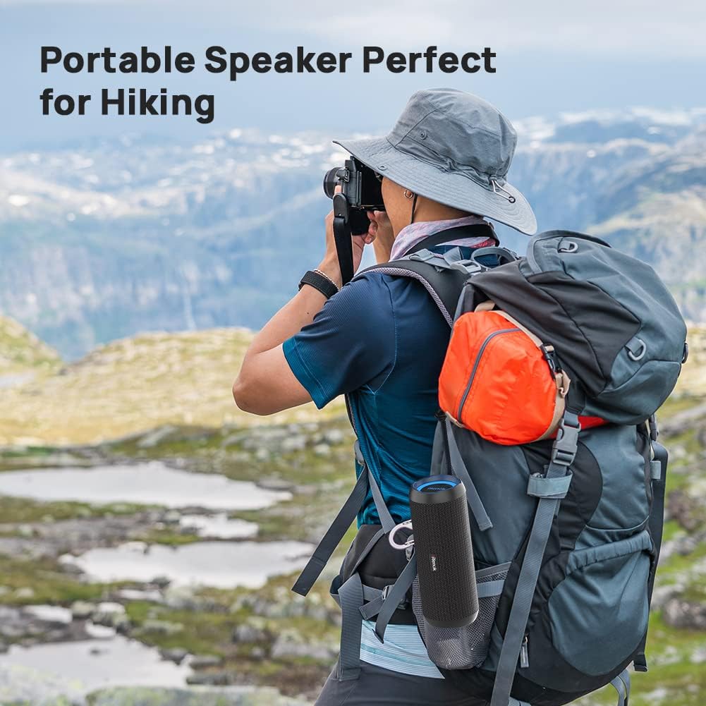 Person hiking with a backpack and portable speaker, set against a mountainous landscape.