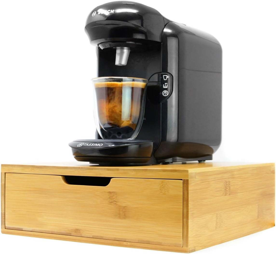 Black coffee machine with a glass of coffee on a wooden stand against a white background