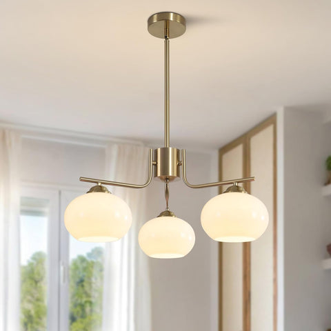 Modern pendant light fixture with three glass shades in a room with a window.