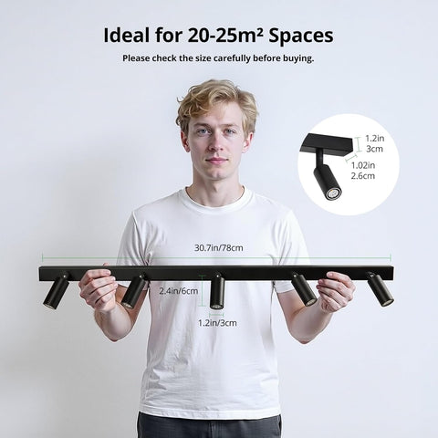 Person holding a long black light fixture with measurements on a plain background