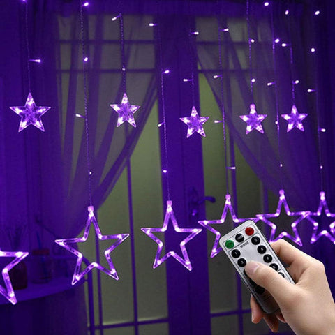Star-shaped LED string lights with a remote control in front of a window.