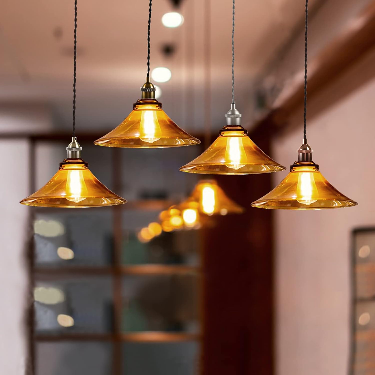 Four pendant lights with gold glass shades hanging in a room.