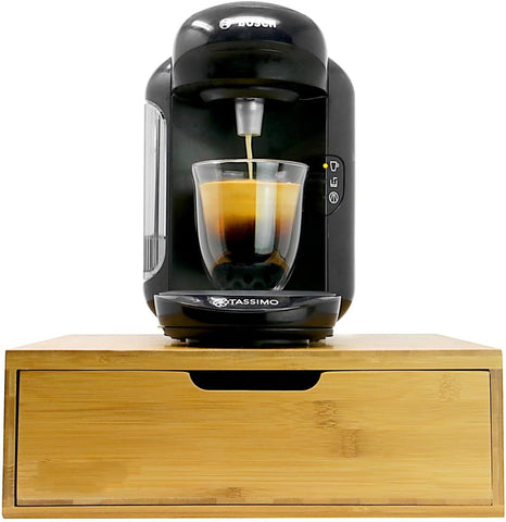 Tassimo coffee machine dispensing coffee into a glass on a wooden stand.