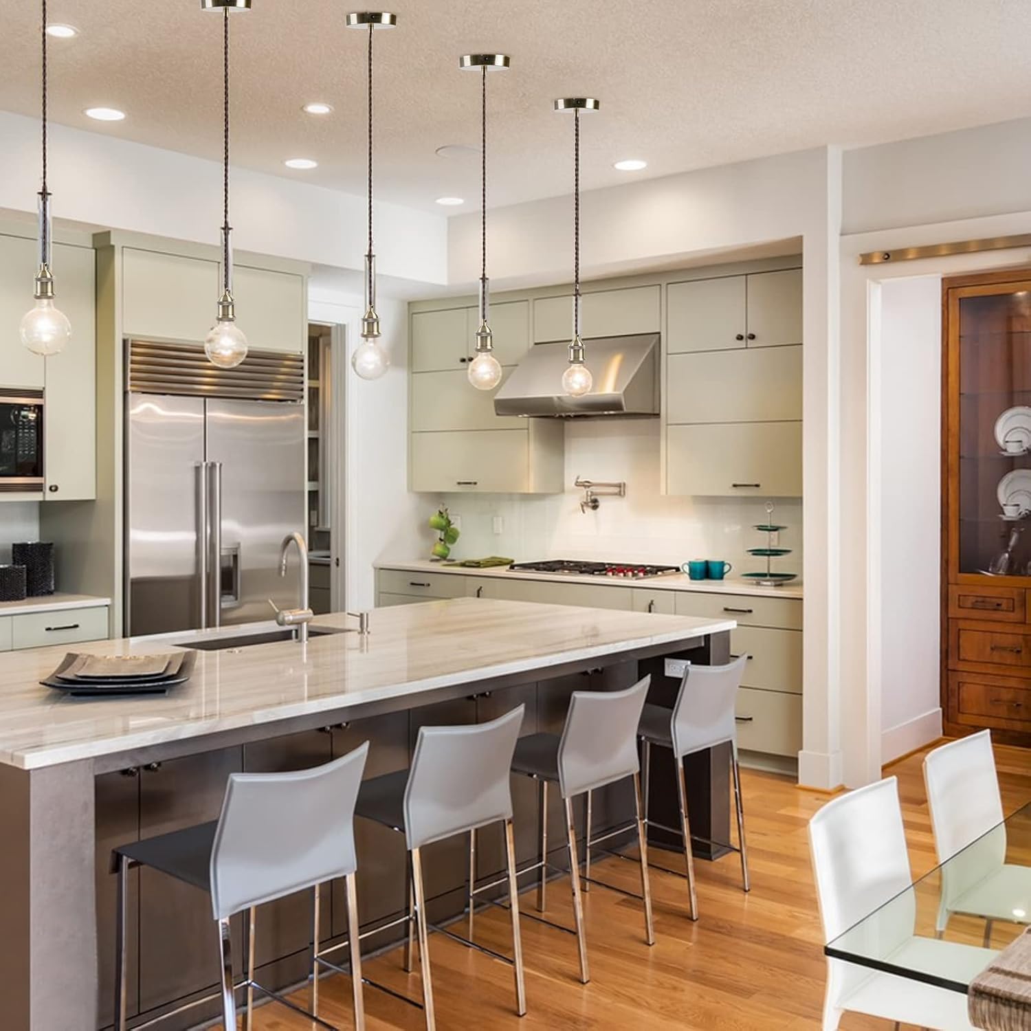 Modern kitchen with island, chairs, and stainless steel appliances.