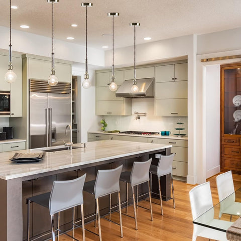 Modern kitchen with island, chairs, and stainless steel appliances.