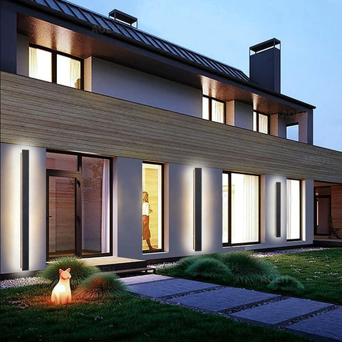 Modern house exterior with illuminated windows and a lit fox figure in the garden.