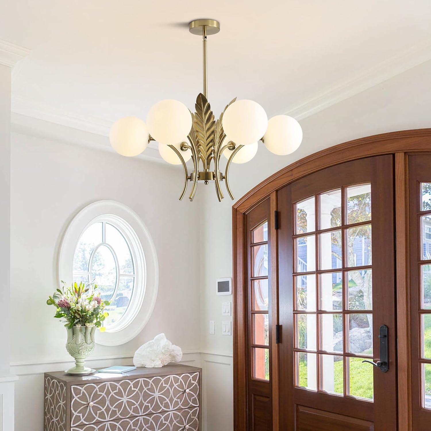 Chandelier hanging in a room with a wooden door and decorative vase.