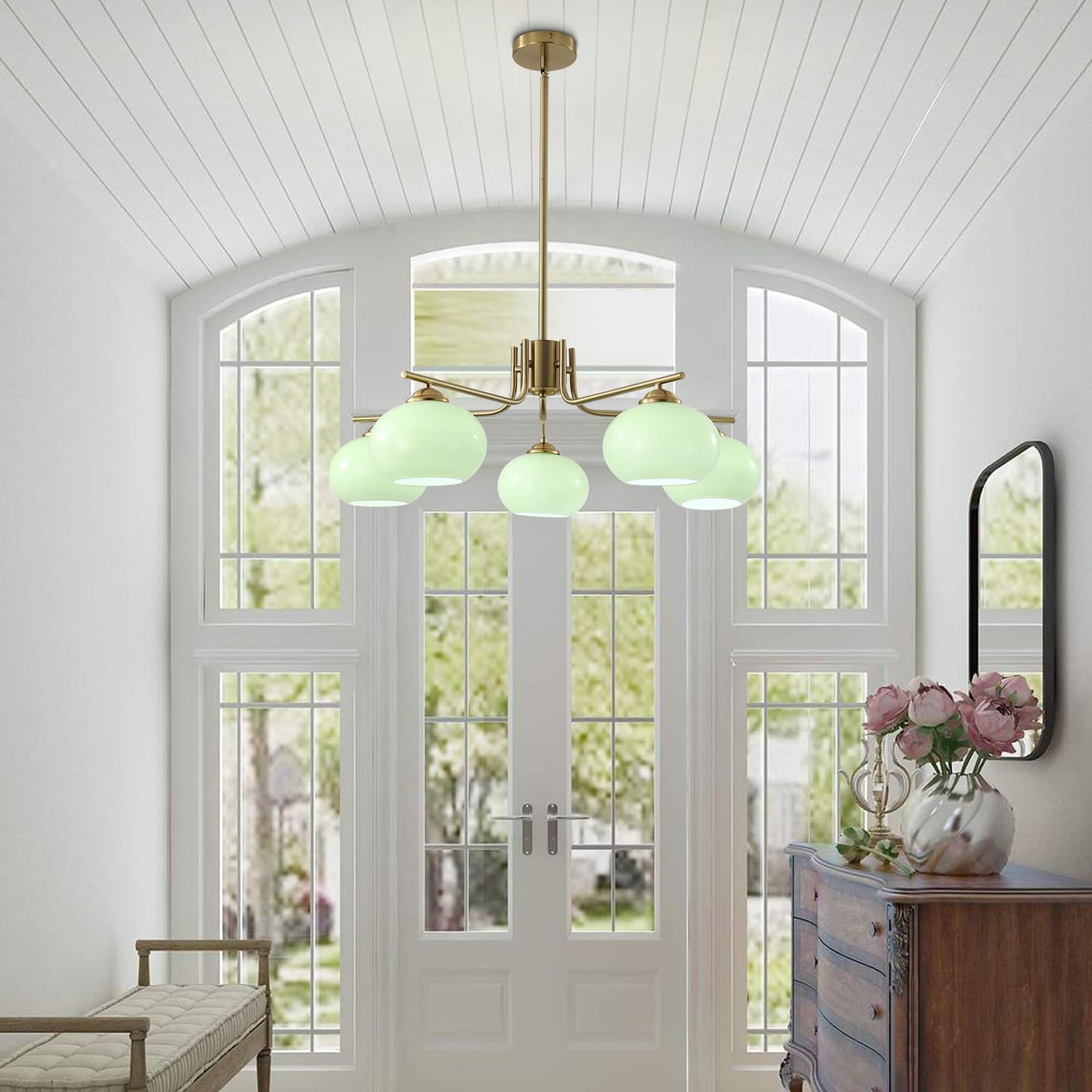 Chandelier with green glass shades in a room with large windows and a wooden cabinet.