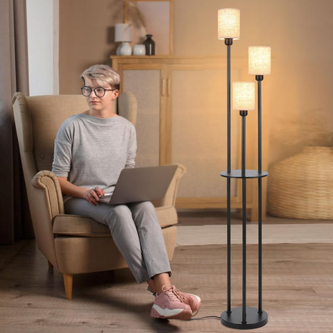 Person sitting in a chair with a laptop, surrounded by floor lamps in a cozy room.