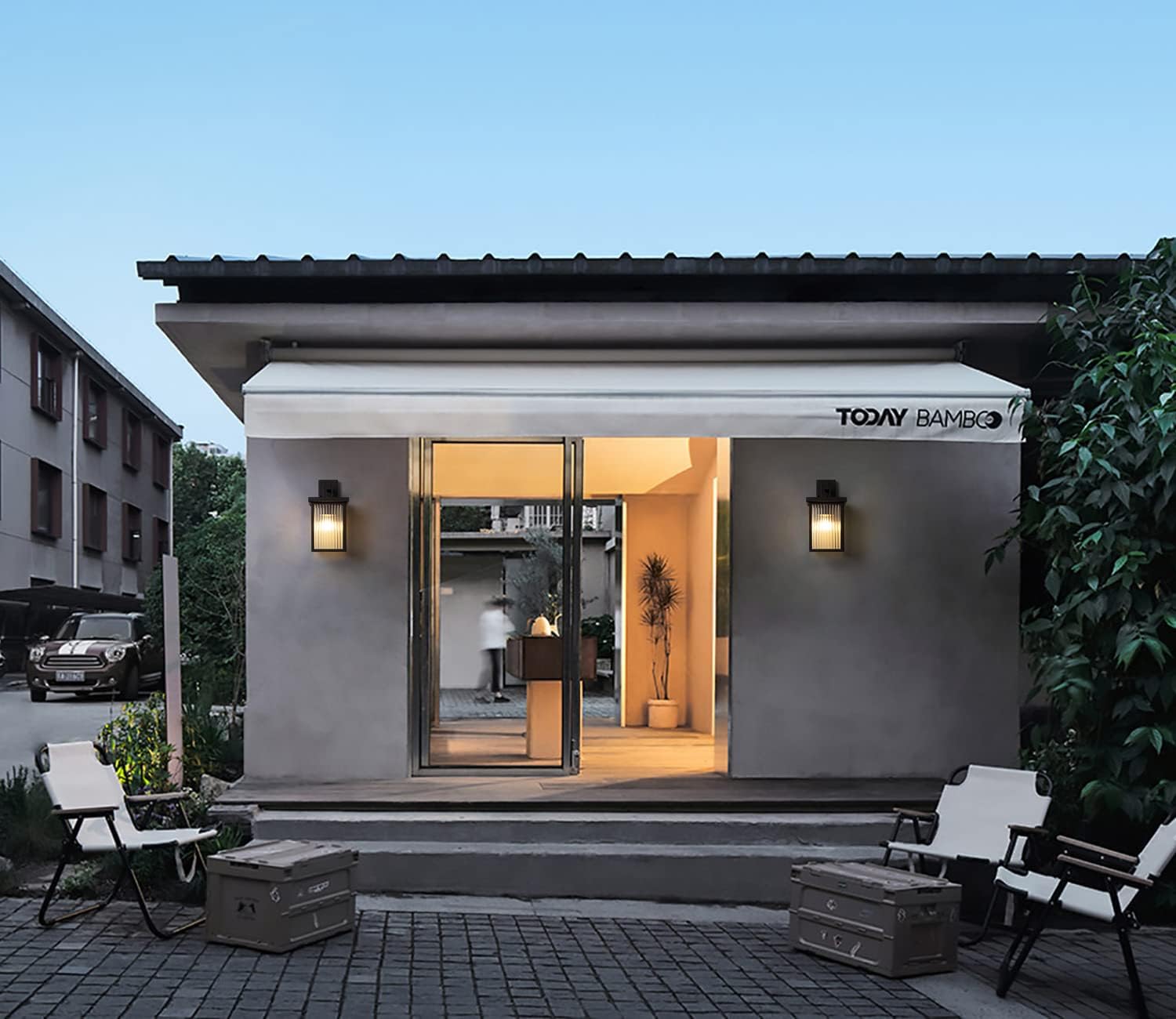 Modern building entrance with 'Tomy' branding, surrounded by greenery and a clear sky.