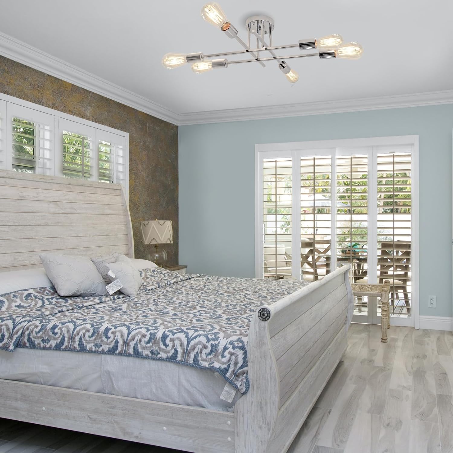 Bedroom with wooden bed, patterned bedding, and a view of a patio through a window.
