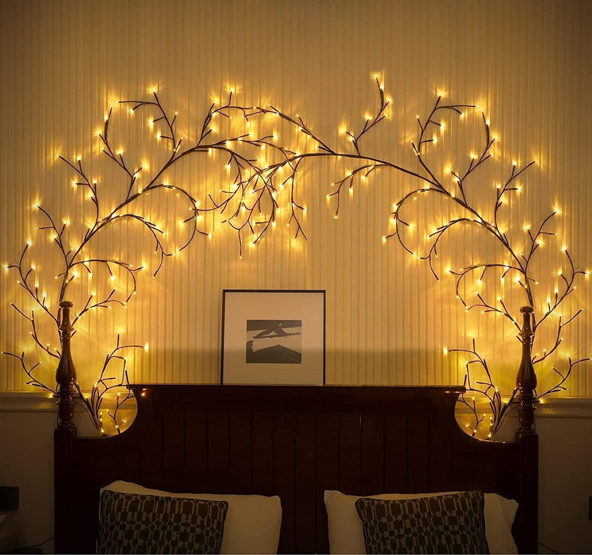 Decorative wall with illuminated branches and a framed picture on a striped wall.
