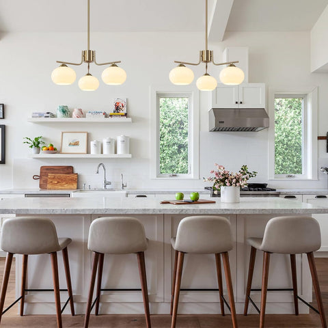 Modern kitchen with white island, stools, and pendant lights.