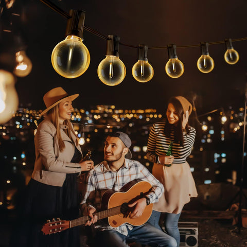 People enjoying a rooftop gathering with string lights and cityscape view