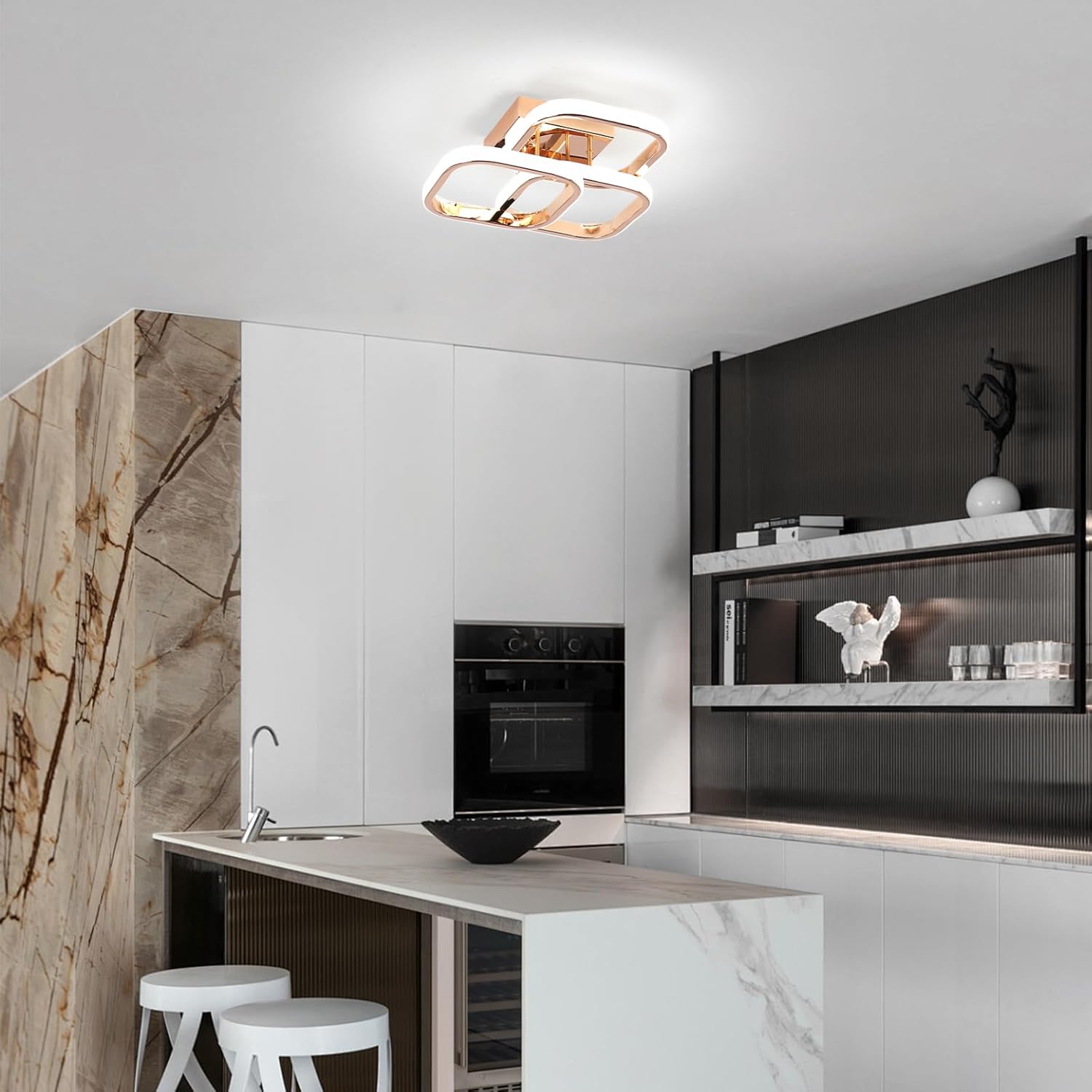 Modern kitchen with marble walls, white cabinets, and black appliances.