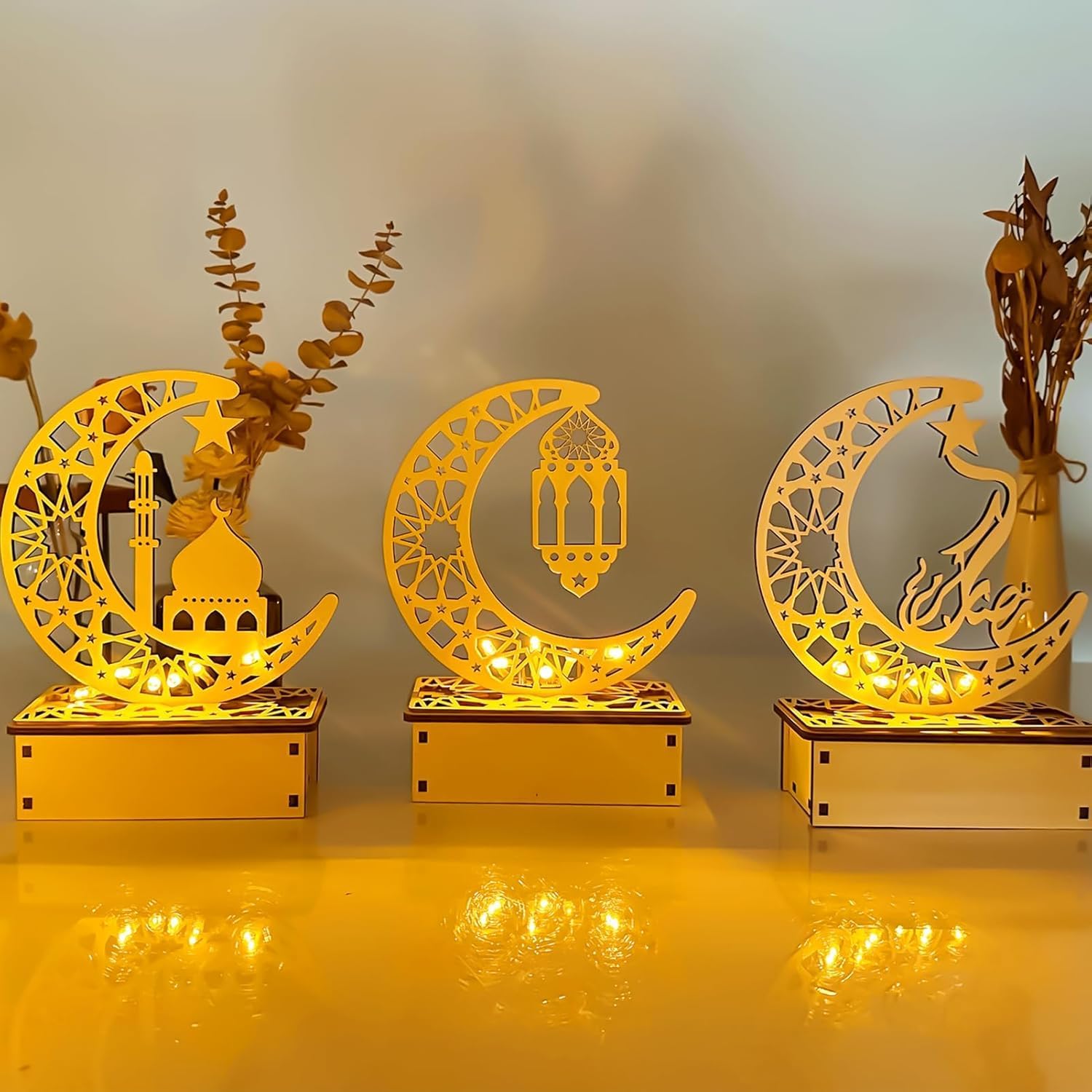 Decorative moon-shaped lamps with intricate designs on a reflective surface.