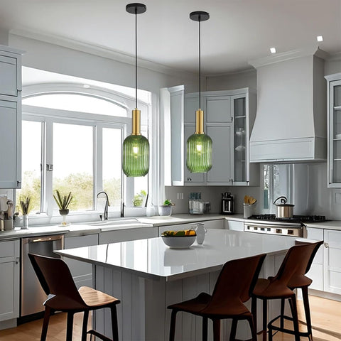 Modern kitchen with green pendant lights, white countertops, and wooden chairs.