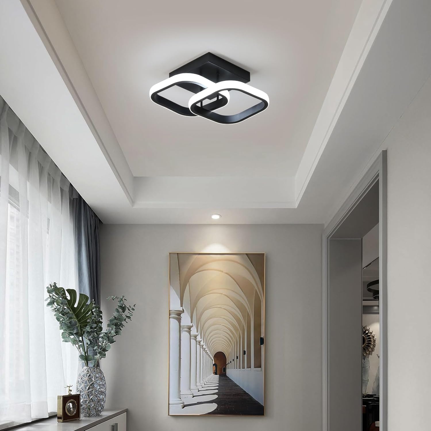 Modern ceiling light fixture in a stylish hallway with a painting on the wall.