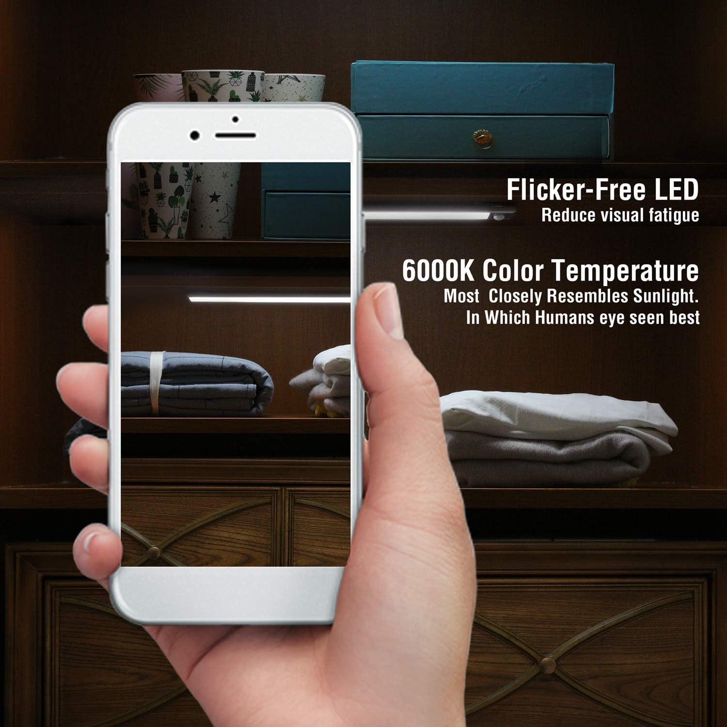 Hand holding a smartphone displaying a room with a dresser, with text about flicker-free LED and color temperature.