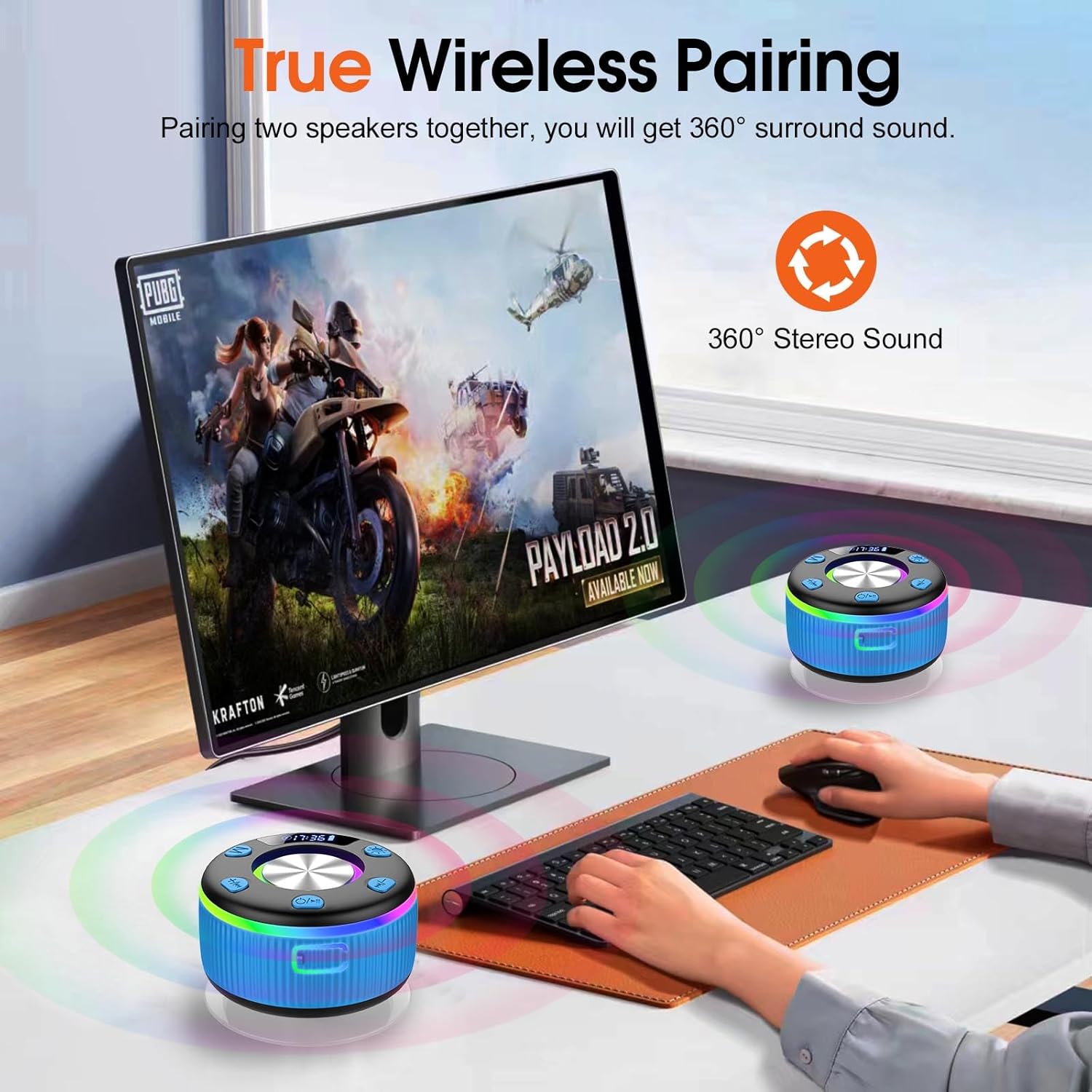 Two wireless speakers on a desk with a computer monitor displaying a game, emphasizing true wireless pairing and 360° stereo sound.