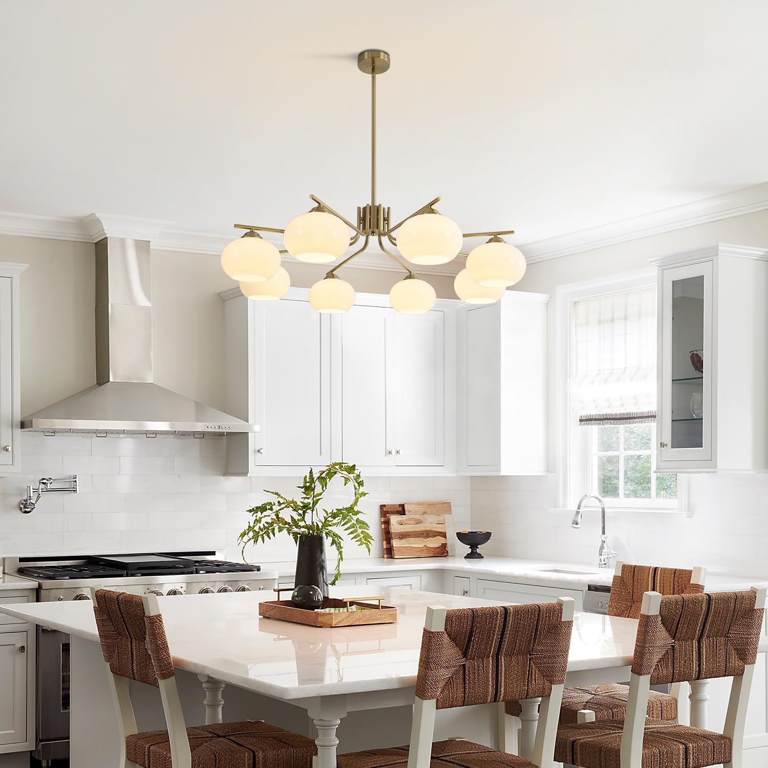 Modern kitchen with a chandelier, white countertops, and wooden chairs.