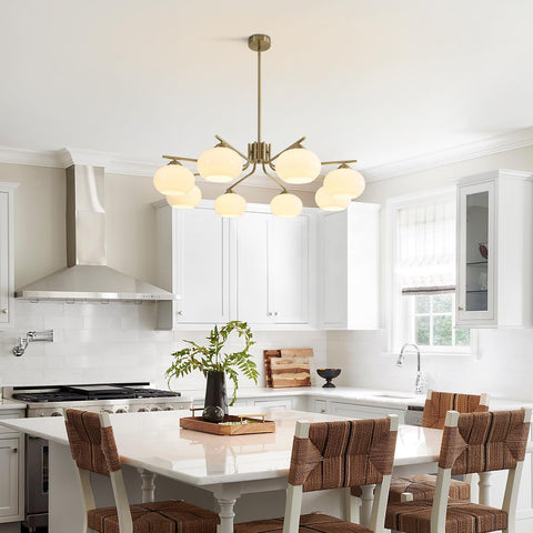 Modern kitchen with a chandelier, white countertops, and wooden chairs.