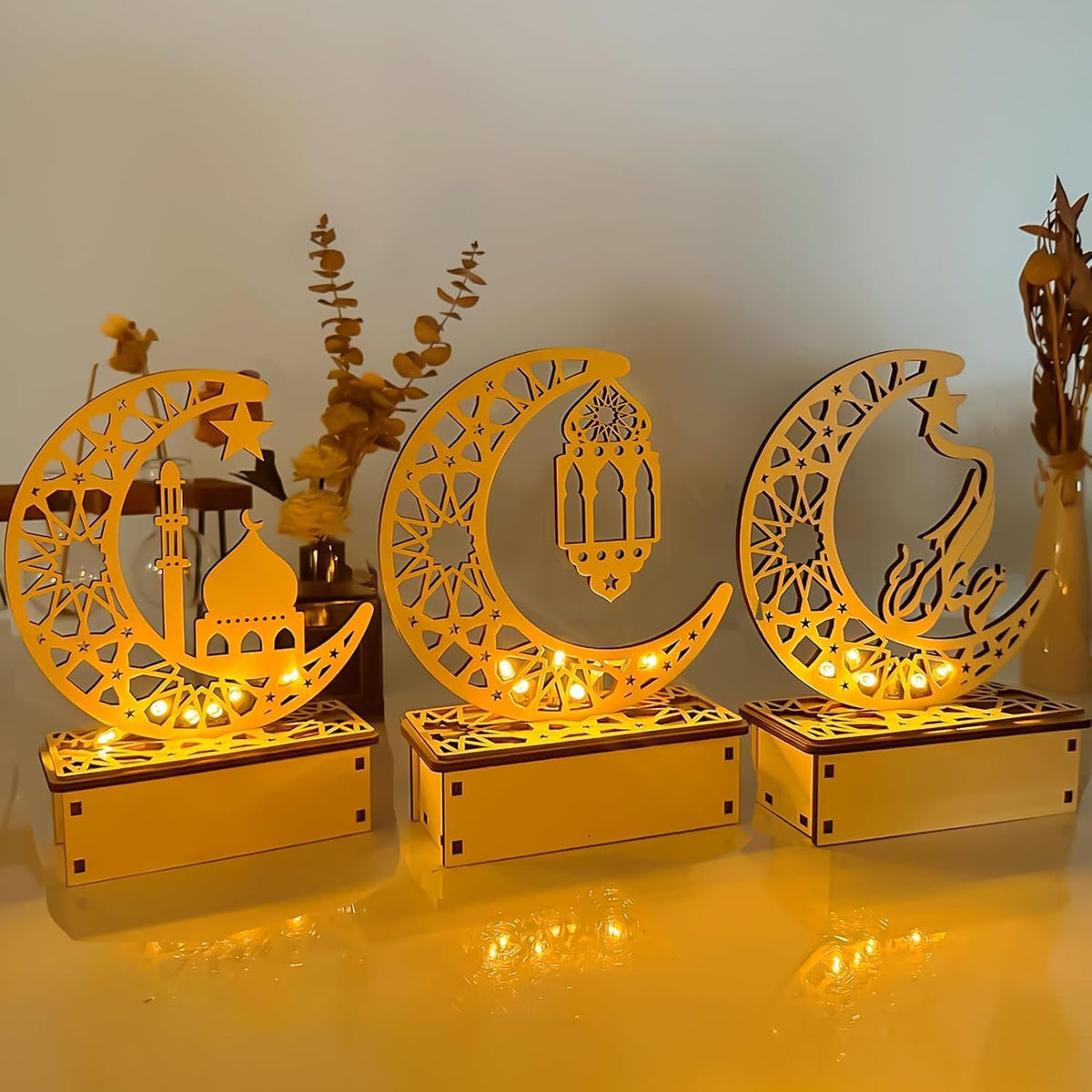 Decorative moon-shaped lamps with intricate designs on a reflective surface.
