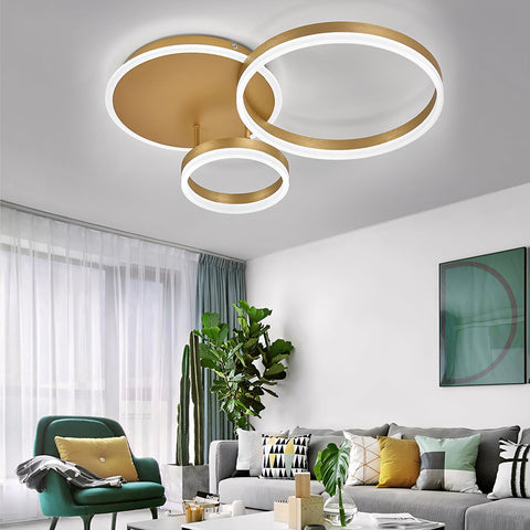 Modern living room with a gold ceiling light fixture, green armchair, and gray sofa.