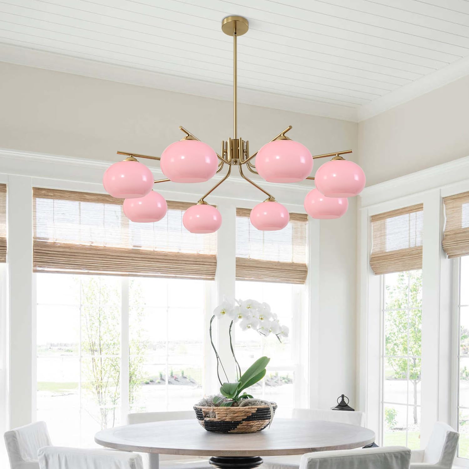 Pink chandelier in a room with large windows and a table with a plant.