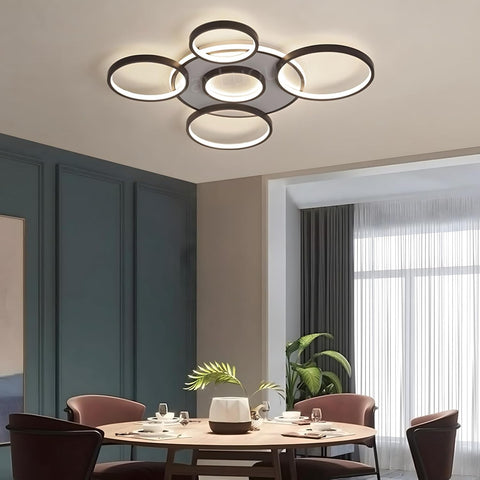Modern ceiling light fixture in a dining room setting with a round table and chairs.