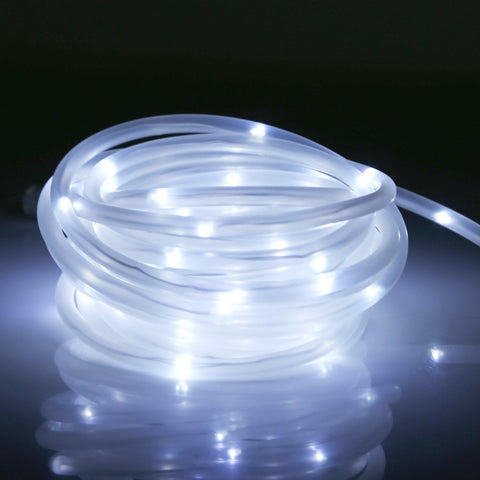 Roll of LED rope lights on a reflective surface with a dark background