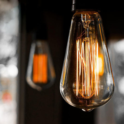Vintage-style light bulb with visible filaments against a dark background