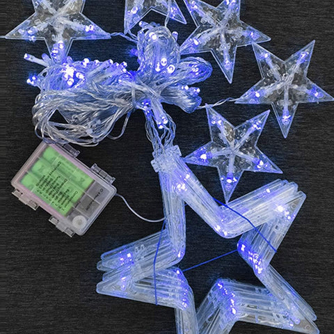 Star-shaped LED string lights with battery pack on a dark surface