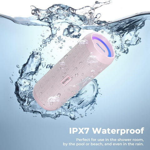 Pink waterproof Bluetooth speaker with water splashes around it on a light blue background.