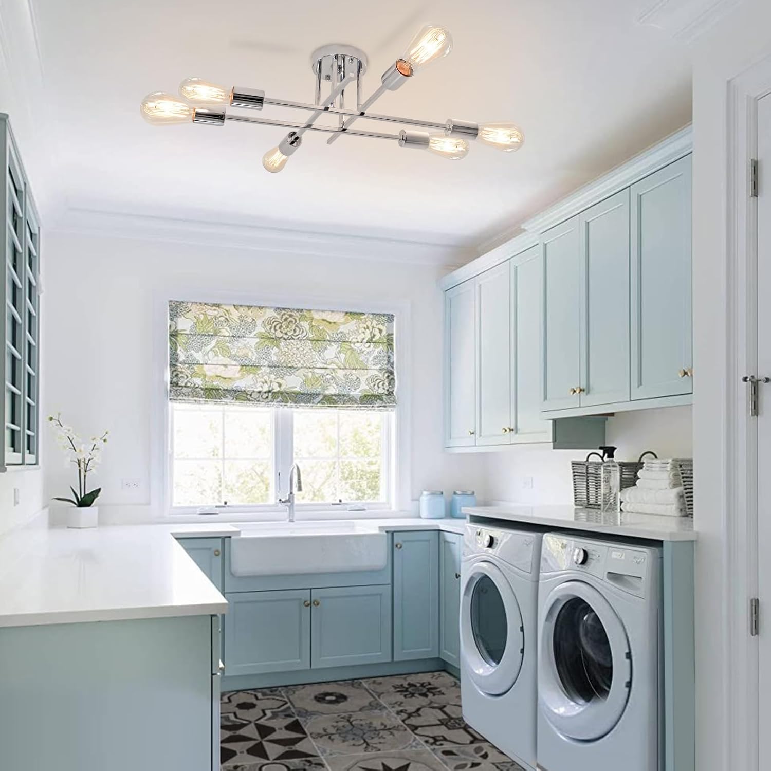 Modern laundry room with light blue cabinets, washer, dryer, and window with greenery outside.