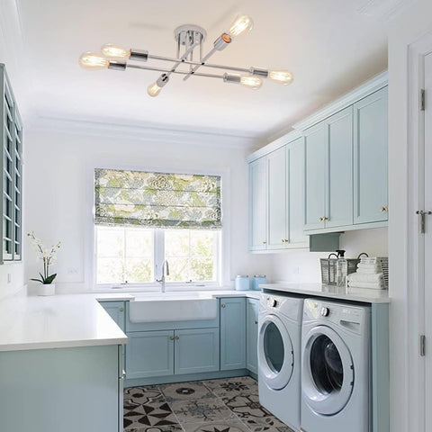 Modern laundry room with light blue cabinets, washer, dryer, and window with greenery outside.