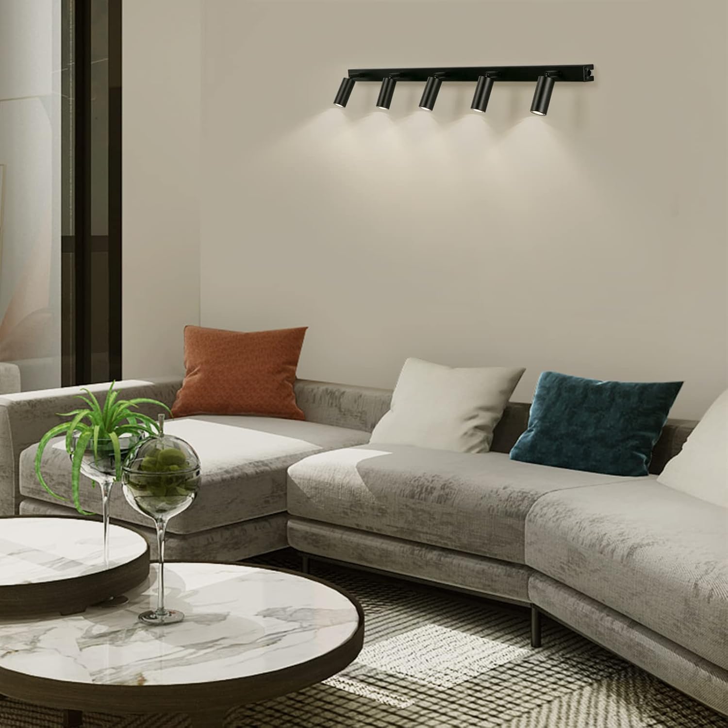 Modern living room with a gray sectional sofa, decorative pillows, and a marble coffee table.