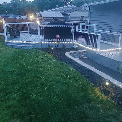Backyard with a deck, garden, and string lights