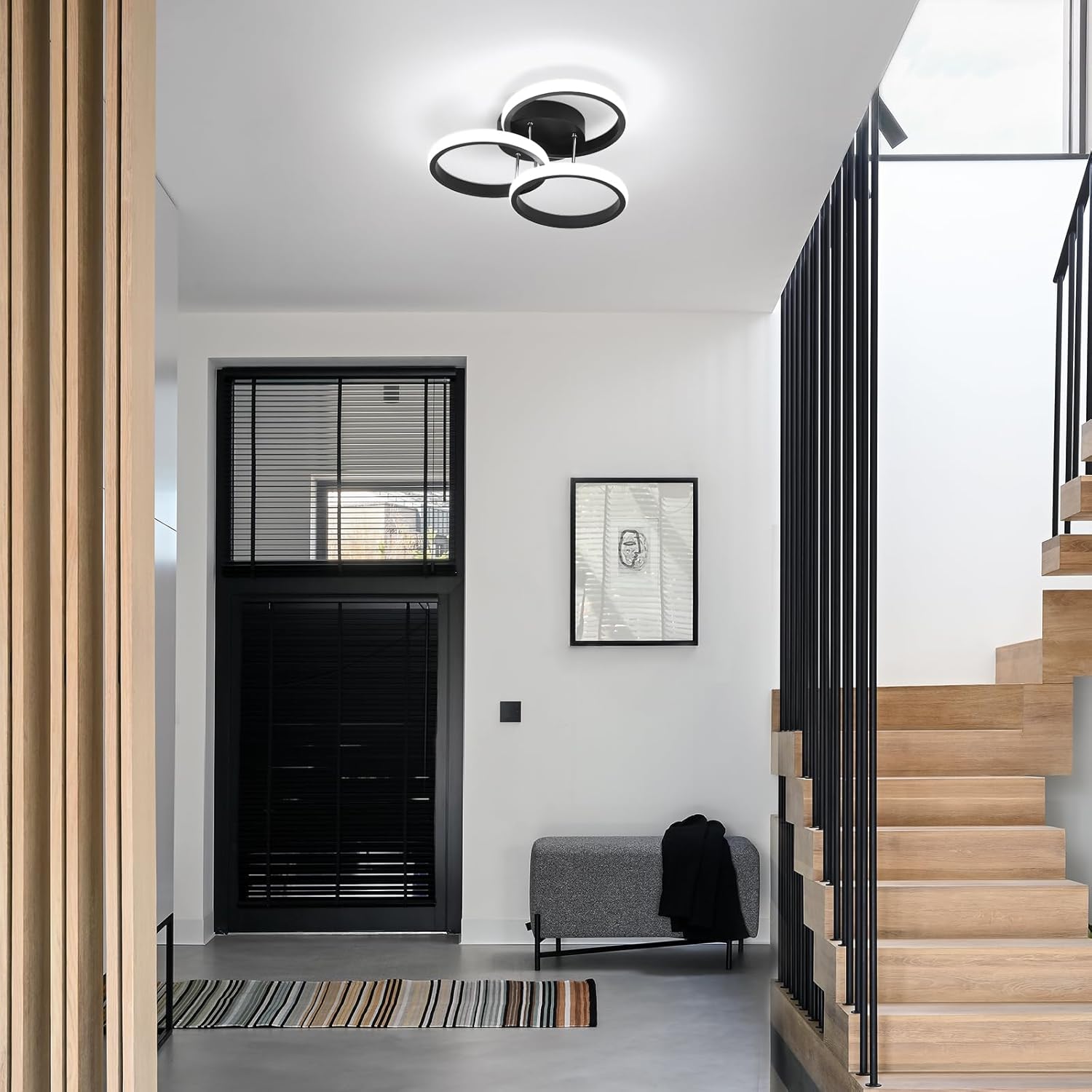 Modern interior with black door, wooden staircase, and ceiling light fixture.