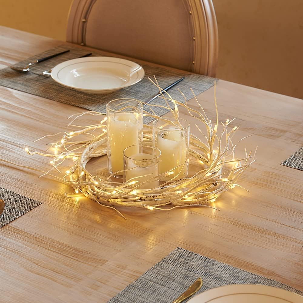 Decorative table setting with candles and fairy lights on a wooden table.