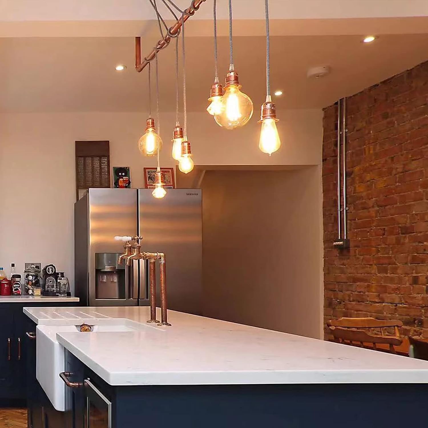 Modern kitchen with pendant lights, refrigerator, and brick wall.