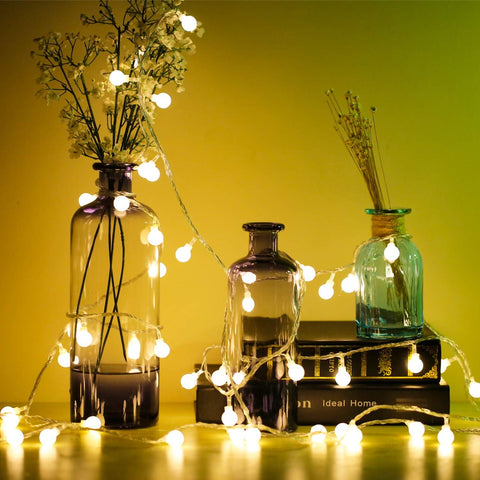 Globe fairy lights draped over a fireplace mantel

