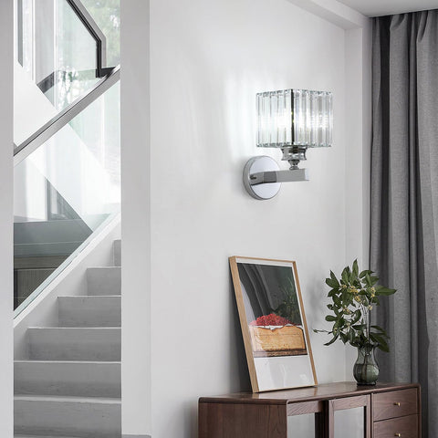 Modern wall sconce on a white wall with a staircase and decorative items in the background.