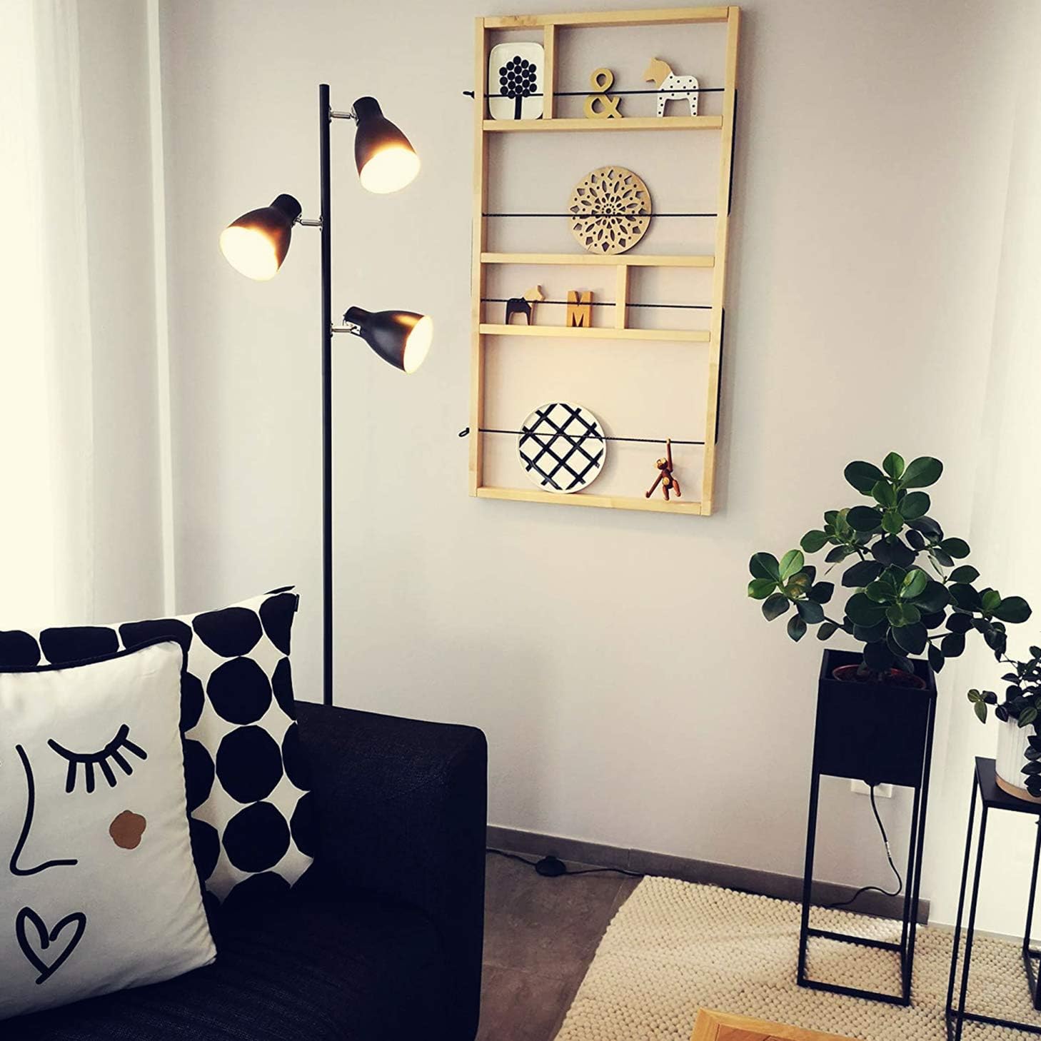 Modern living room with a black sofa, floor lamp, and decorative wall shelf.